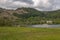 Panorama of Loch Achray surrounded by mountains and manor of Mor Trossachs
