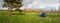 Panorama of the lush green spring meadows, tent and trees