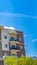 Panorama Lush trees in front of a building with red brick wall and small balconies