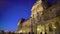 Panorama of majestic Louvre Palace building illuminated at night, many tourists