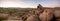 Panorama of man hiking among field of boulders at dusk with sunset sky Yucca Valley California near Joshua Tree National Park on