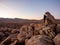 Panorama of man hiking among field of boulders at dusk with sunset sky Yucca Valley California near Joshua Tree National Park on a