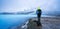 Panorama of Man with hiking gear who stands on volcanic rock looking towards Geothermal powerplant at the blue lagoon in Jarabodin