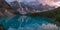 Panorama of The Moraine lake sunset with snow with turquoise lake and cloudy sunset sky