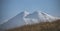 Panorama of Mount Elbrus with snow and glaciers at side evening illumination and yellowed autumn grass in the mountains