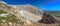 Panorama of the mountain landscape. A crumbling mountain range with remnants of last year's snow against a blue sky.