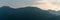 Panorama mountain landscape in silhouette with wispy cloudy sky in the blue hour