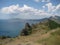 Panorama of mountain range against blue sea and sunny sky with white cumulus clouds,  extinct volcano Karadag, Crimea