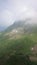 Panorama of the mountains and of the Aibga ridge with low clouds. Remains of snow and fresh green grass on the mountains near the