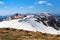 Panorama with mountains. The top of the hills covered with snow. The lawn with dried grass. Tourist resting place. Spring day.