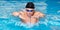 Panorama of Muscular swimmer young man in black cap in swimming pool, performing butterfly stroke.