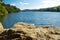 Panorama of a natural body of water with a rock in the foreground in a forest landscape. Brno Reservoir - Czech Republic