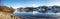 Panorama of nearly frozen Oltedalsvatnet lake and coastline with mountains peaks covered by snow during winter season