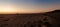 Panorama of the Oregon coast beach with a magnificent sunset and people taking a stroll