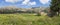 Panorama overlooking the small wooden cottages in Njegusi village, standing in a row on a green plain against the mountains on a h