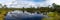 Panorama of a peat bog and blue lake landscape under an expressive sky with white clouds