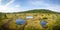 Panorama of peat bog with little lakes under blue sky