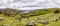 Panorama picture of typical Irish landscape with green meadows and rough mountains