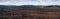 panorama of plowed field and a field of winter wheat in the hilly terrain with cloudly sky