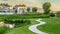 Panorama Pond and pathway on a scenic park in front of sunlit houses under cloudy sky