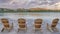 Panorama Puffy clouds at sunset Four wooden lounge chairs facing the reflective Oquirrh Lake at