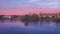 Panorama of a purple sunset with a rural landscape with houses on the lake.