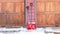 Panorama Red shovels on snowy driveway against wall and wooden garage doors of home