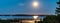 Panorama of rising full golden Moon over Umea river delta, summer night with clear skies and tiny white fog over water and coast