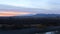 Panorama of a river at dusk with a sunset beyond the distant mountains zoom as the camera pans