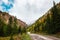 Panorama of road to the gorge of mountains on background of beautiful snowy mountain peaks in cloudy weather. Mountain