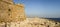 Panorama of a rocky beach and Paphos Castle back wall