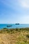 A panorama seascape view with rocky islands along the coast under a majestic blue sky and some white clouds