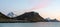 Panorama shot of mountain peaks in Lofoten with pink skies overhead.