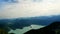 Panorama shot of natural lake after hike on hills with outstand alp mountain silhouette between clouds in summer