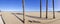 Panorama shot of a nearly empty beach with four palm trees and in the distance the port of Valencia, Spain