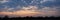 Panorama, silhouettes of trees against a cloudy sky at sunset