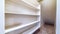 Panorama Small walk in closet with empty long cabinet shelves under slanted ceiling