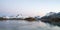 Panorama of Snow covered mountains and powerful streams in the ocean during blue hour in Flakstad