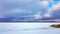 Panorama of snowy lake with lonely sportsman doing winter kiting