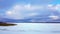 Panorama of snowy lake with lonely sportsman doing winter kiting