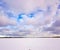 Panorama of snowy lake with lonely sportsman doing winter kiting