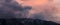 Panorama of storm clouds hovering over snow capped mountains at sunset near Bishop, California, USA