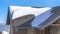 Panorama Sunlit gray pitched roof of a home with mound of fresh snow at winter season