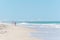 Panorama of a sunny beach with some brown seaweed laying in the coarse sand, a stunning blue and wavy ocean and kids
