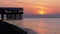 Panorama of the sunset over the sea next to the silhouette of the pier.