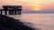 Panorama of the sunset over the sea next to the silhouette of the pier.