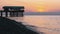 Panorama of the sunset over the sea next to the silhouette of the pier.