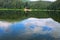 Panorama of Synevyr lake on summer morning. Gorgeous scenery with spruce forest reflecting on a water surface.