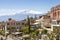 Panorama of Taormina with white peak of smoking volcano Etna