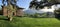 Panorama of the territory of a Villa Madruzzo at sunset, huge trees, ideal green lawns, facade of buildings, Picturesque